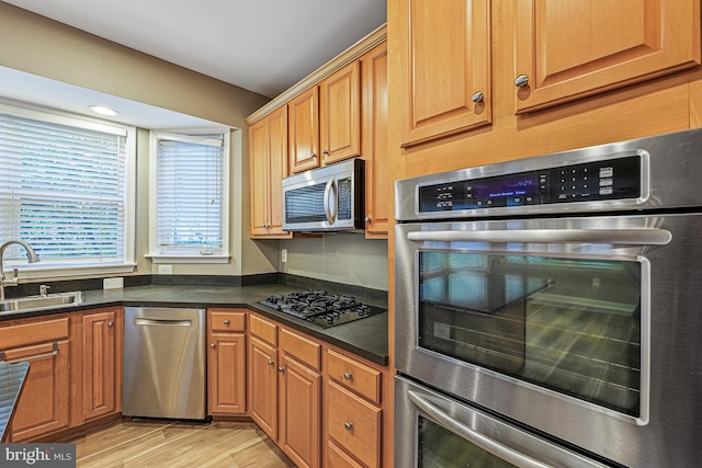 46825 Northbrook Way, Sterling, VA 20164 - kitchen with stainless steel appliances, a sink, dark countertops, light wood-type flooring, and brown cabinetry