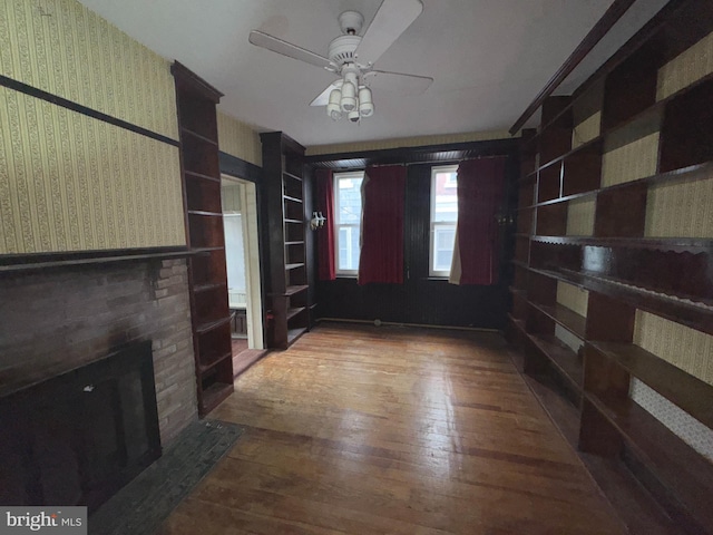 1515 N Franklin St, Wilmington, DE 19806 - unfurnished living room featuring wood-type flooring, wallpapered walls, ceiling fan, a brick fireplace, and built in features