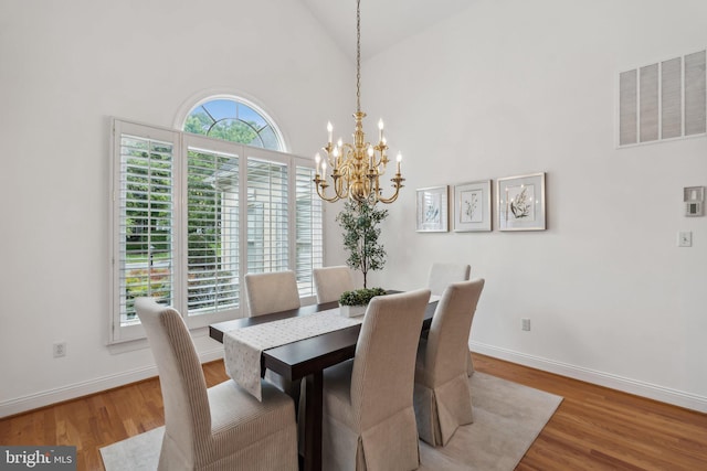 8109 Crooked Oaks Ct, Gainesville, VA 20155 - dining space featuring a chandelier, wood finished floors, high vaulted ceiling, and baseboards
