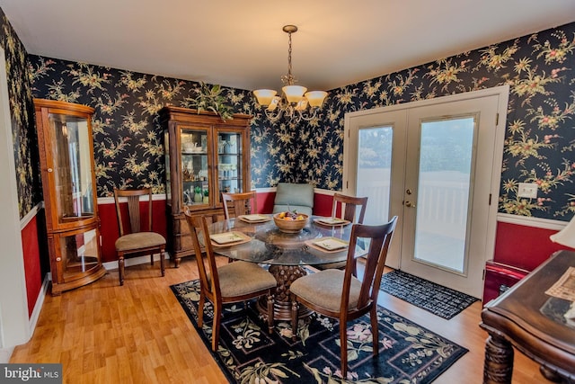 27836 Clearwater Ct, Salisbury, MD 21801 - dining space featuring french doors, wallpapered walls, wood finished floors, a chandelier, and a wainscoted wall