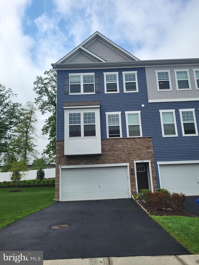 340 Dawson Pl, Downingtown, PA 19335 - townhome / multi-family property with stone siding, driveway, an attached garage, and a front lawn