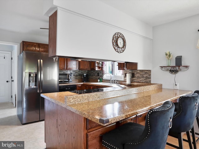123 Windy Meadows Ct, Front Royal, VA 22630 - kitchen with black appliances, a peninsula, a sink, decorative backsplash, and a kitchen bar