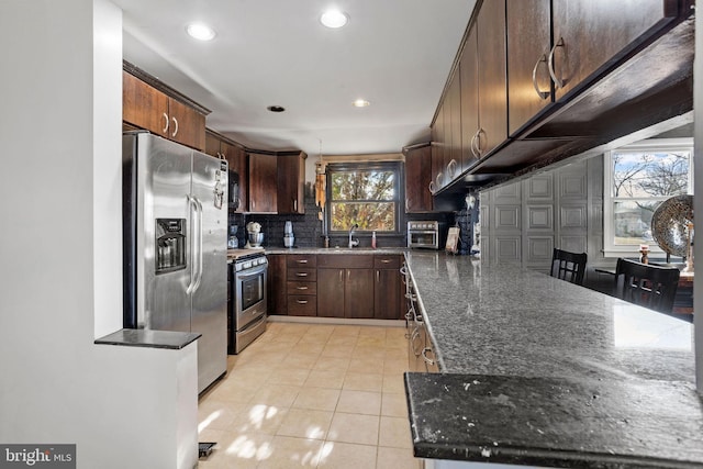 2300 Andover Rd, Cinnaminson, NJ 08077 - kitchen featuring appliances with stainless steel finishes, decorative backsplash, dark stone counters, light tile patterned floors, and a sink
