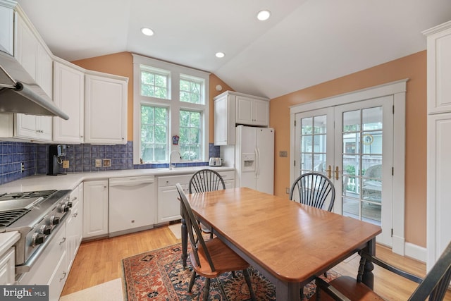 103 E Monroe Ave, Alexandria, VA 22301 - kitchen featuring white appliances, healthy amount of natural light, light wood-type flooring, wall chimney exhaust hood, and lofted ceiling