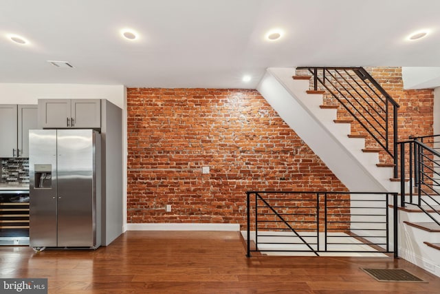 5724 Pine St, Philadelphia, PA 19143 - kitchen with stainless steel refrigerator with ice dispenser, brick wall, baseboards, wood finished floors, and gray cabinets