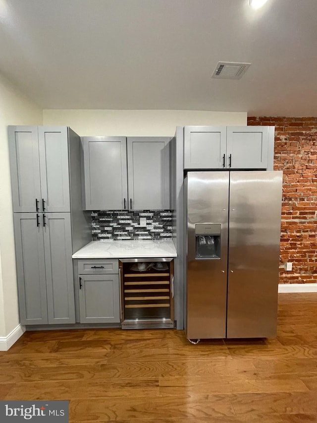 5724 Pine St, Philadelphia, PA 19143 - indoor dry bar with stainless steel fridge, beverage cooler, light wood-type flooring, tasteful backsplash, and baseboards