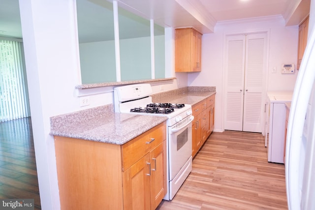 10248 Prince Pl Unit 23-102, Upper Marlboro, MD 20774 - kitchen featuring white gas range, light wood finished floors, crown molding, washing machine and clothes dryer, and light brown cabinetry
