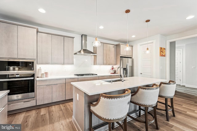 42023 Spring Air Dr, Brambleton, VA 20148 - kitchen featuring wall chimney exhaust hood, stainless steel appliances, a sink, a kitchen bar, and light countertops