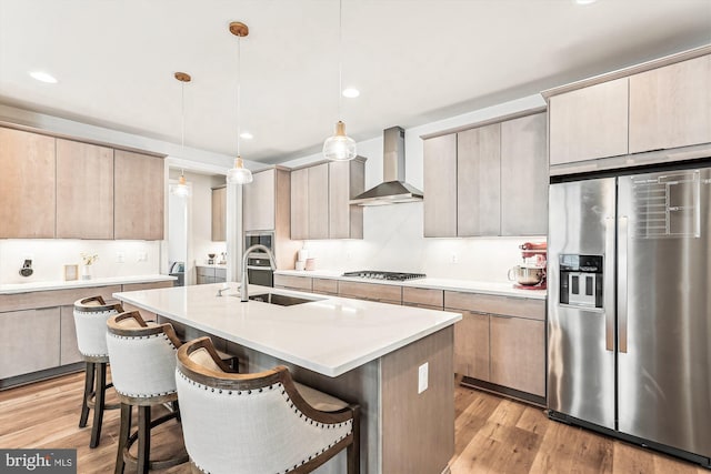 42023 Spring Air Dr, Brambleton, VA 20148 - kitchen featuring stainless steel appliances, wall chimney range hood, a sink, light wood-type flooring, and a breakfast bar area