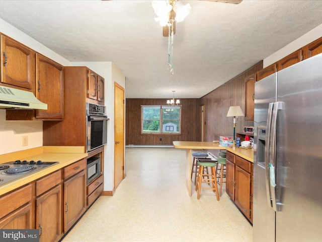 717 W Locust St, Woodstock, VA 22664 - kitchen featuring appliances with stainless steel finishes, ventilation hood, a chandelier, light countertops, and brown cabinets