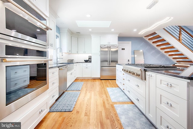 714 Alliance St, Havre De Grace, MD 21078 - kitchen featuring stainless steel appliances, a skylight, light wood finished floors, decorative backsplash, and a sink