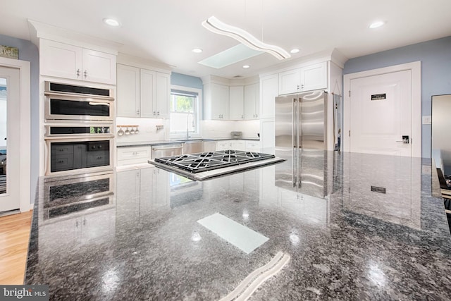 714 Alliance St, Havre De Grace, MD 21078 - kitchen with stainless steel appliances, white cabinets, dark stone counters, tasteful backsplash, and decorative light fixtures