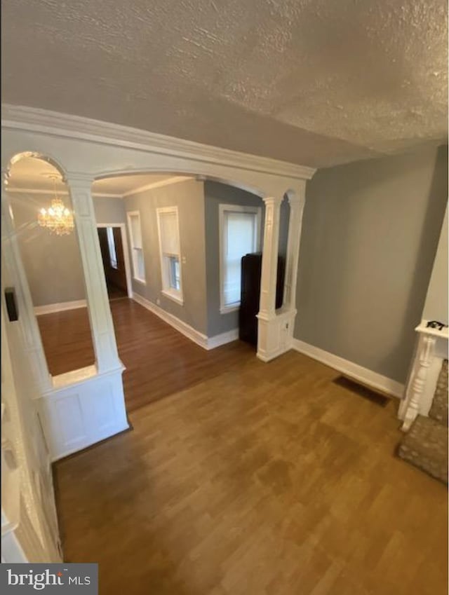 4216 Wyalusing Ave, Philadelphia, PA 19104 - empty room with arched walkways, a textured ceiling, wood finished floors, decorative columns, and baseboards