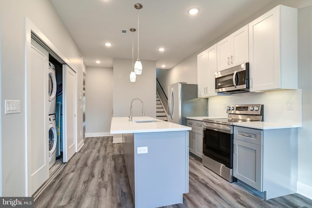 5005 Walnut St, Philadelphia, PA 19139 - kitchen featuring appliances with stainless steel finishes, stacked washing machine and dryer, a sink, wood finished floors, and recessed lighting
