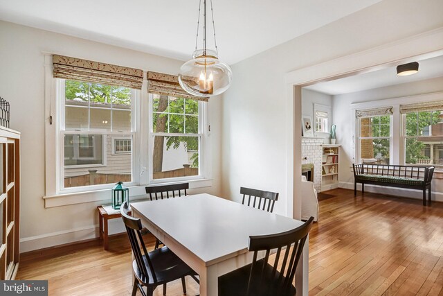 815 Aspen St NW, Washington, DC 20012 - dining space with light wood-style flooring, a chandelier, baseboards, and a brick fireplace