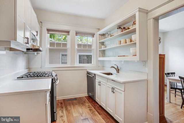 815 Aspen St NW, Washington, DC 20012 - kitchen with appliances with stainless steel finishes, a sink, open shelves, light wood-type flooring, and decorative backsplash
