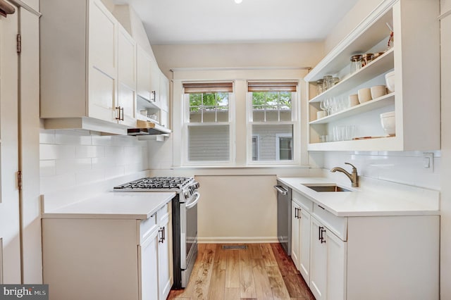 815 Aspen St NW, Washington, DC 20012 - kitchen with appliances with stainless steel finishes, open shelves, a sink, light countertops, and light wood-style floors