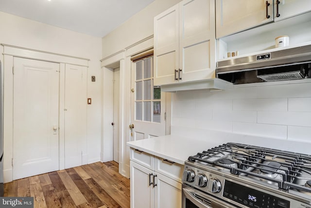 815 Aspen St NW, Washington, DC 20012 - kitchen featuring gas range, decorative backsplash, light countertops, wood finished floors, and under cabinet range hood