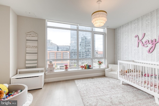 1330 Lancaster St Unit C701, Baltimore, MD 21231 - bedroom with wallpapered walls, a crib, light wood finished floors, a chandelier, and a view of city