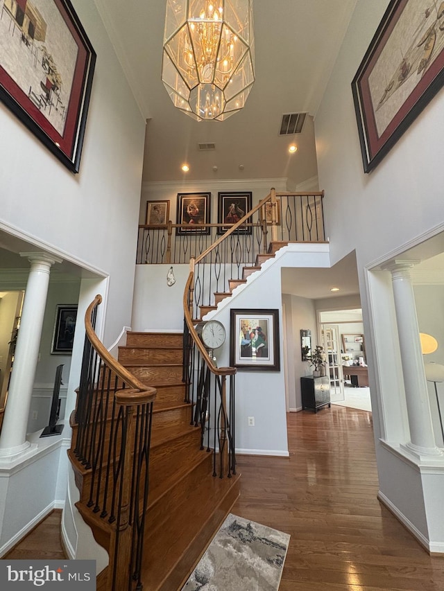 7633 Great Dover St, Gainesville, VA 20155 - stairway with ornate columns, wood finished floors, a towering ceiling, baseboards, and a chandelier