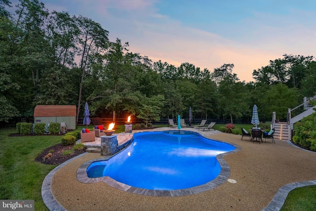 7633 Great Dover St, Gainesville, VA 20155 - pool at dusk featuring a patio area, a shed, a lawn, stairway, and a fire pit