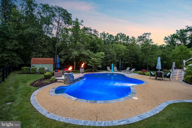 7633 Great Dover St, Gainesville, VA 20155 - pool at dusk with a patio, an outdoor pool, view of scattered trees, and a storage shed