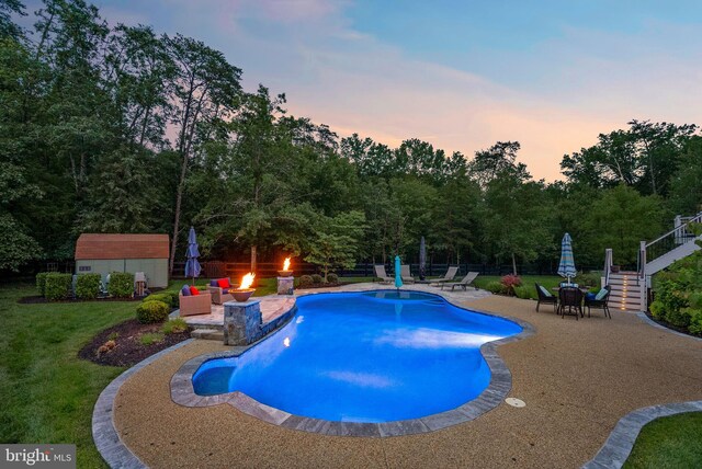 7633 Great Dover St, Gainesville, VA 20155 - pool at dusk featuring a patio area, a shed, a lawn, stairway, and a fire pit