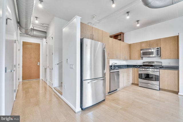 811 4th St NW Unit 320, Washington, DC 20001 - kitchen with stainless steel appliances, a sink, light wood-style floors, dark countertops, and baseboards