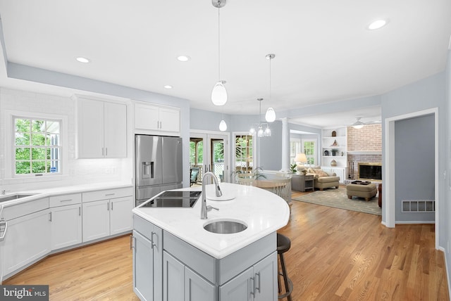 20783 Laplume Pl, Ashburn, VA 20147 - kitchen with stainless steel fridge, a sink, a brick fireplace, a kitchen bar, and light countertops
