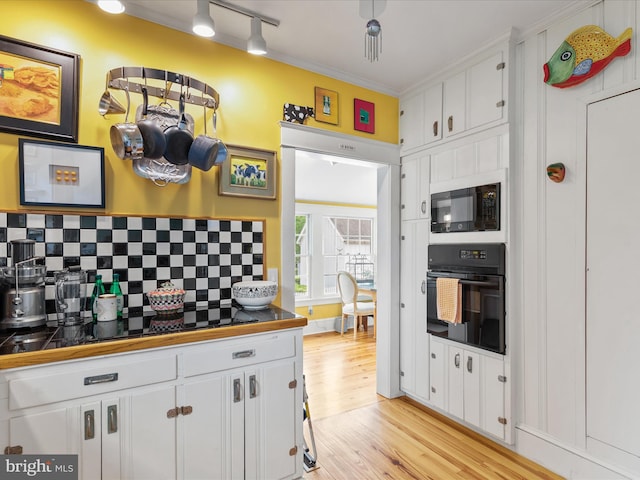 417 S Main St, Berlin, MD 21811 - kitchen featuring black appliances, white cabinetry, backsplash, light wood-style flooring, and rail lighting