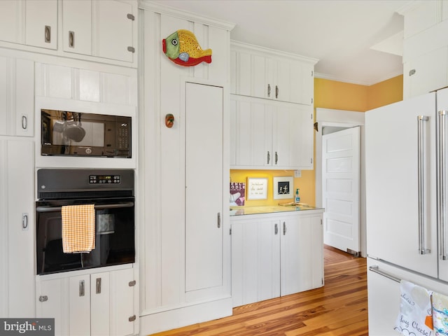 417 S Main St, Berlin, MD 21811 - kitchen featuring black appliances, light wood-type flooring, white cabinetry, light countertops, and ornamental molding