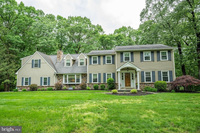 276 Cherry Ln, Doylestown, PA 18901 - colonial home with stone siding, a chimney, a front lawn, and view of wooded area