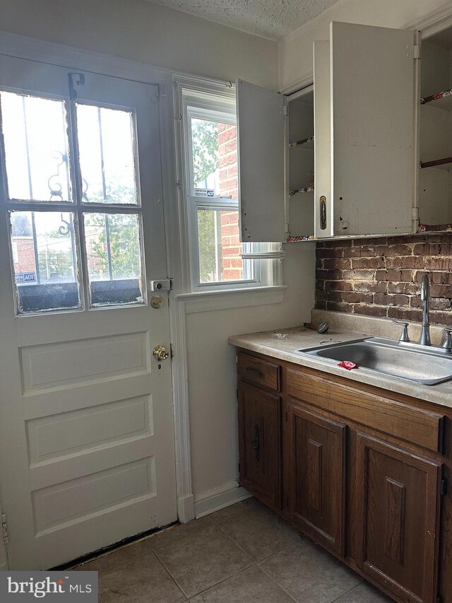 1902 T St SE, Washington, DC 20020 - kitchen featuring a sink, light tile patterned flooring, light countertops, decorative backsplash, and a textured ceiling