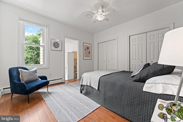 1205 G St NE, Washington, DC 20002 - bedroom with a baseboard radiator, two closets, light wood-style flooring, and a ceiling fan
