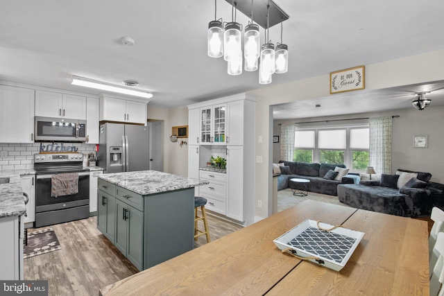 1980 State Route 72 N, Lebanon, PA 17046 - kitchen featuring appliances with stainless steel finishes, white cabinetry, open floor plan, light wood-type flooring, and decorative backsplash