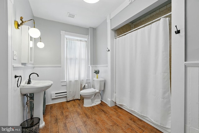 706 Locust St, Cambridge, MD 21613 - bathroom with a baseboard radiator, a wainscoted wall, toilet, wood finished floors, and curtained shower