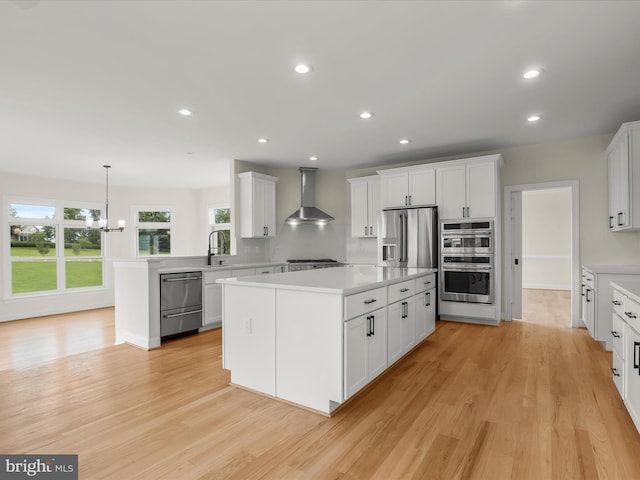 6419 Homebuilder Dr, Mount Airy, MD 21771 - kitchen with wall chimney exhaust hood, appliances with stainless steel finishes, light countertops, a kitchen island, and white cabinetry