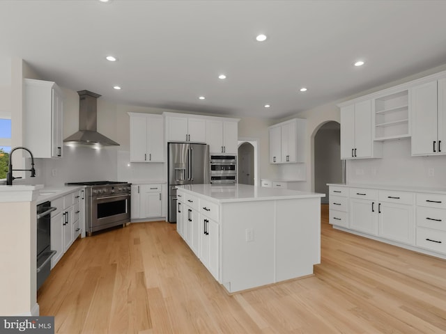 6419 Homebuilder Dr, Mount Airy, MD 21771 - kitchen featuring stainless steel appliances, wall chimney exhaust hood, arched walkways, a sink, and a center island