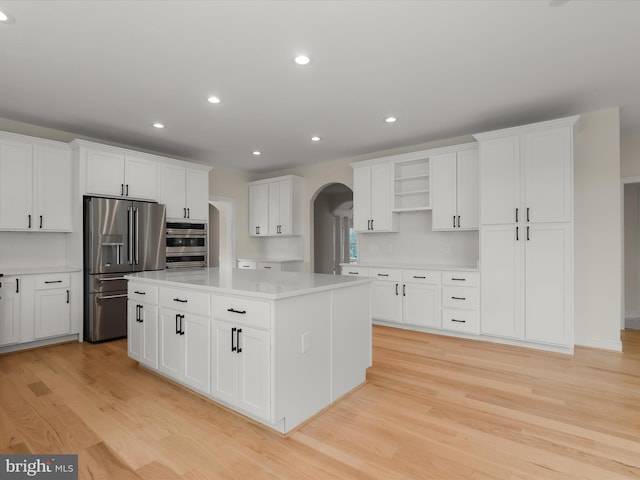 6419 Homebuilder Dr, Mount Airy, MD 21771 - kitchen with appliances with stainless steel finishes, arched walkways, light wood finished floors, a center island, and white cabinets