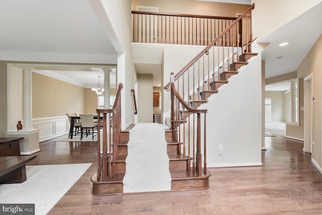 42435 Ibex Dr, Sterling, VA 20166 - stairway featuring decorative columns, wood finished floors, crown molding, plenty of natural light, and a towering ceiling