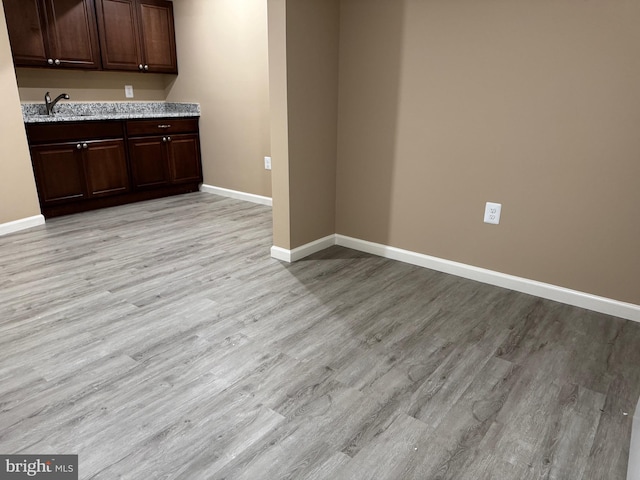 42435 Ibex Dr, Sterling, VA 20166 - kitchen featuring baseboards, light wood finished floors, dark brown cabinets, a sink, and light stone counters