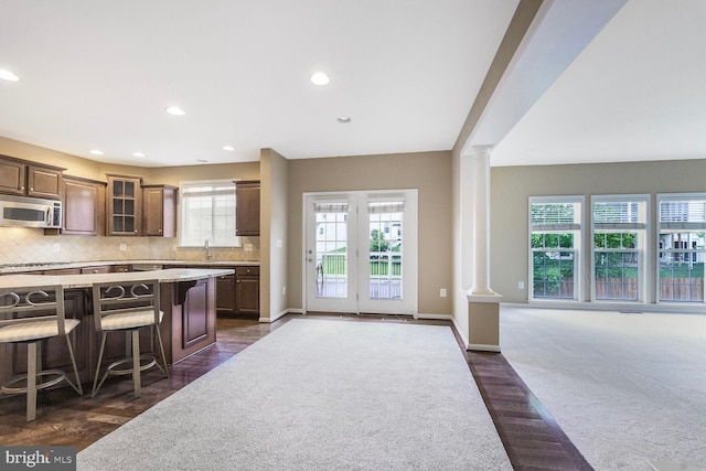 42435 Ibex Dr, Sterling, VA 20166 - kitchen featuring stainless steel microwave, decorative columns, glass insert cabinets, a kitchen bar, and recessed lighting