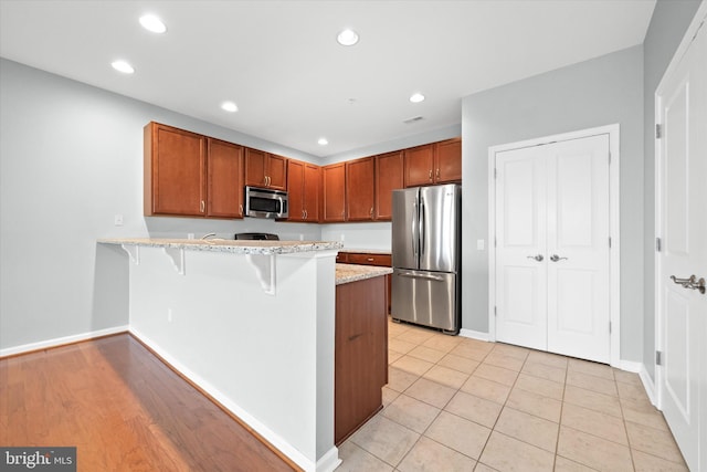 113 E Main St Unit 303, Newark, DE 19711 - kitchen with appliances with stainless steel finishes, a peninsula, a breakfast bar, recessed lighting, and light stone countertops