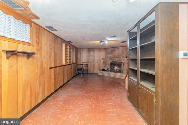 243 Park Ave, Mount Joy, PA 17552 - unfurnished living room featuring wood walls, a fireplace, a textured ceiling, and brick patterned floors