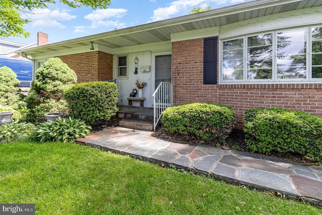 243 Park Ave, Mount Joy, PA 17552 - view of exterior entry featuring brick siding, a lawn, and a chimney