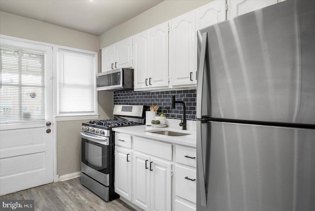 7509 Durwood Rd, Baltimore, MD 21222 - kitchen with stainless steel appliances, a sink, tasteful backsplash, baseboards, and white cabinetry
