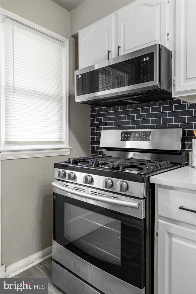 7509 Durwood Rd, Baltimore, MD 21222 - kitchen featuring stainless steel appliances, tasteful backsplash, white cabinetry, baseboards, and wood finished floors