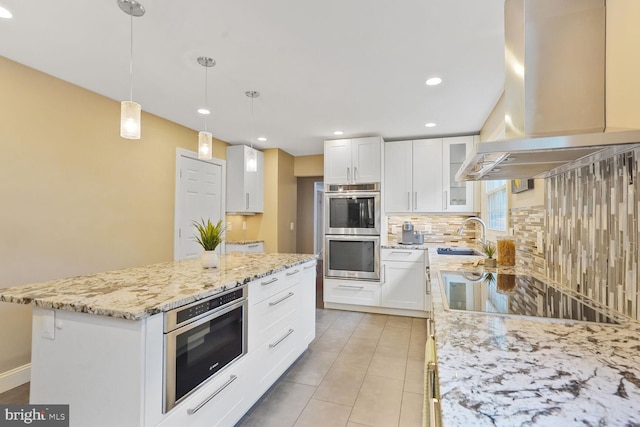 6034 Burnside Landing Dr, Burke, VA 22015 - kitchen featuring island exhaust hood, a sink, double oven, decorative backsplash, and light stone counters