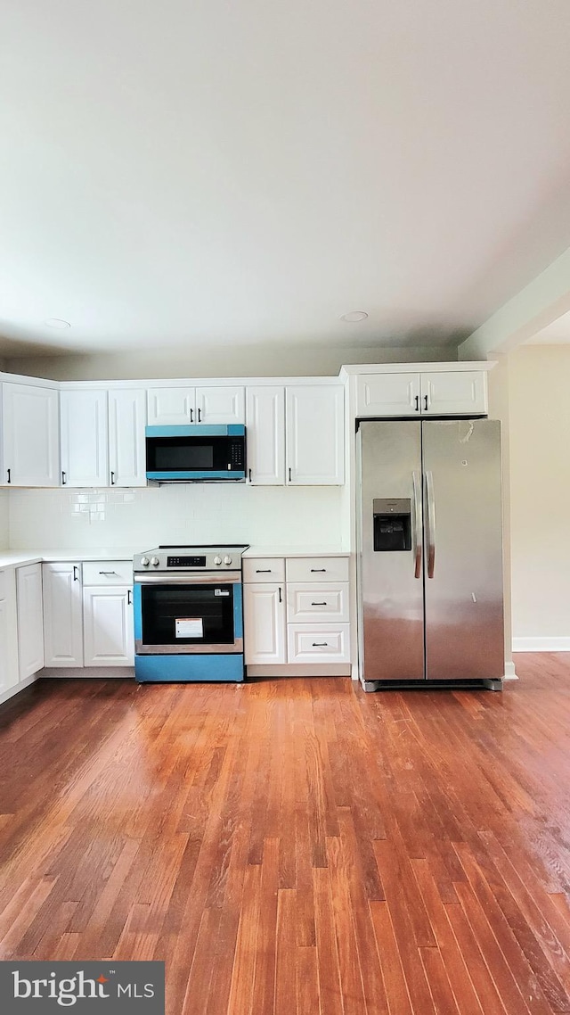139 Wilmington Pl SE, Washington, DC 20032 - kitchen with appliances with stainless steel finishes, light wood-type flooring, white cabinets, light countertops, and decorative backsplash