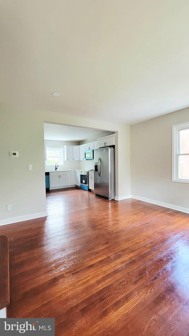 139 Wilmington Pl SE, Washington, DC 20032 - unfurnished living room featuring dark wood-style floors, baseboards, and a sink